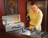 Drain cleaning technician de-clogging a blocked kitchen sink. 